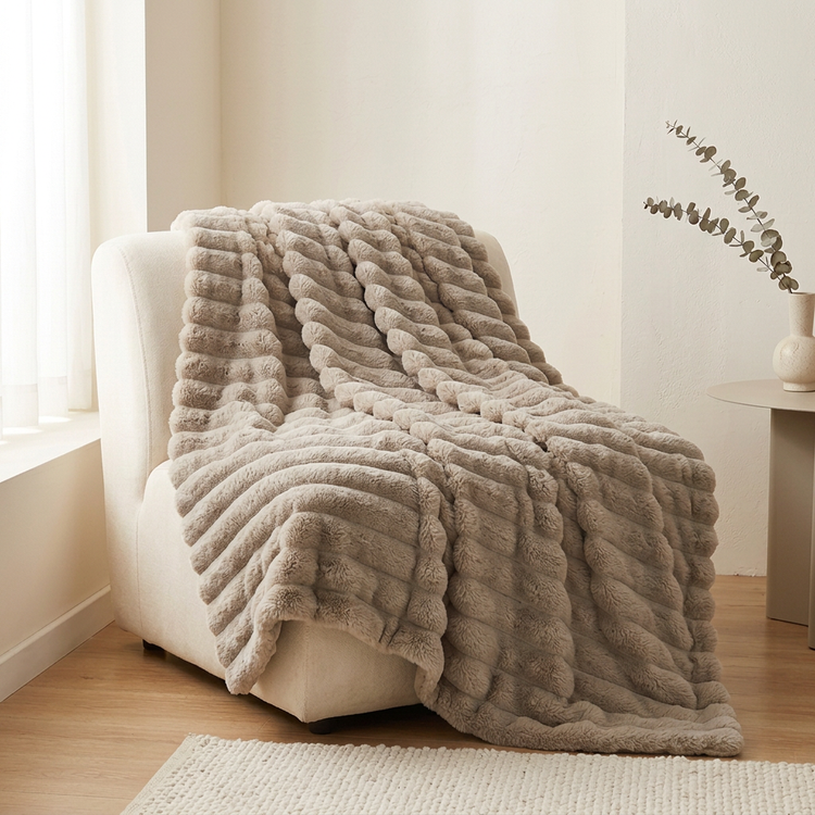Mise en scène du plaid côtelé beige taupe sur un fauteuil crème.
